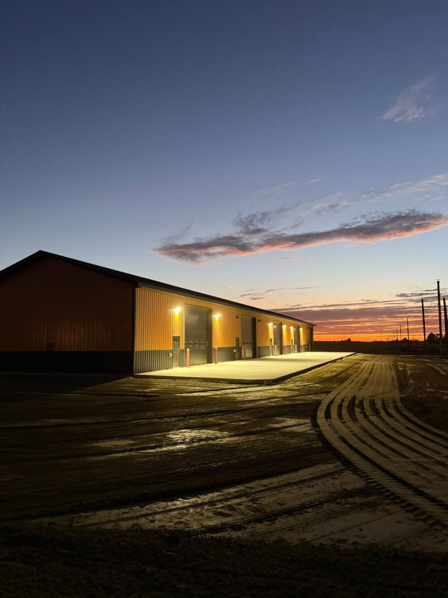 Copper Creek shop condos lit at dusk with a concrete approach in Rugby, North Dakota