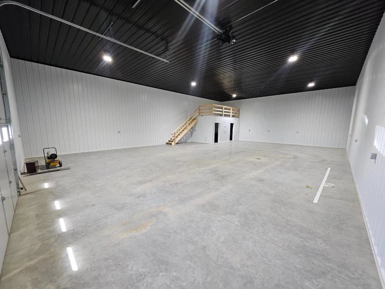 Finished shop condo interior with polished concrete floor, white steel walls, and a loft